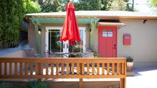 granny pod in backyard with bench, red garden parasol and red door
