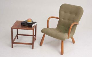 A lounge chair in light green with a brown wooden side table.
