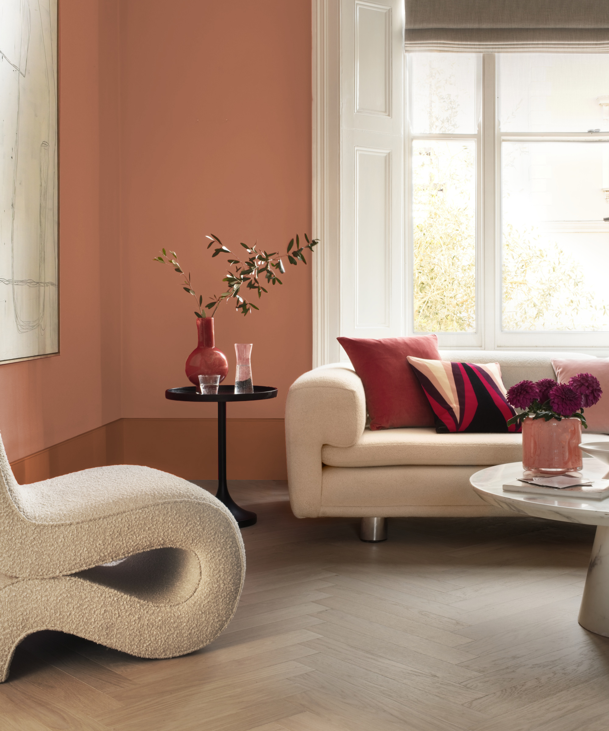 Living room with herringbone flooring, white sofa and chair, peach coloured walls