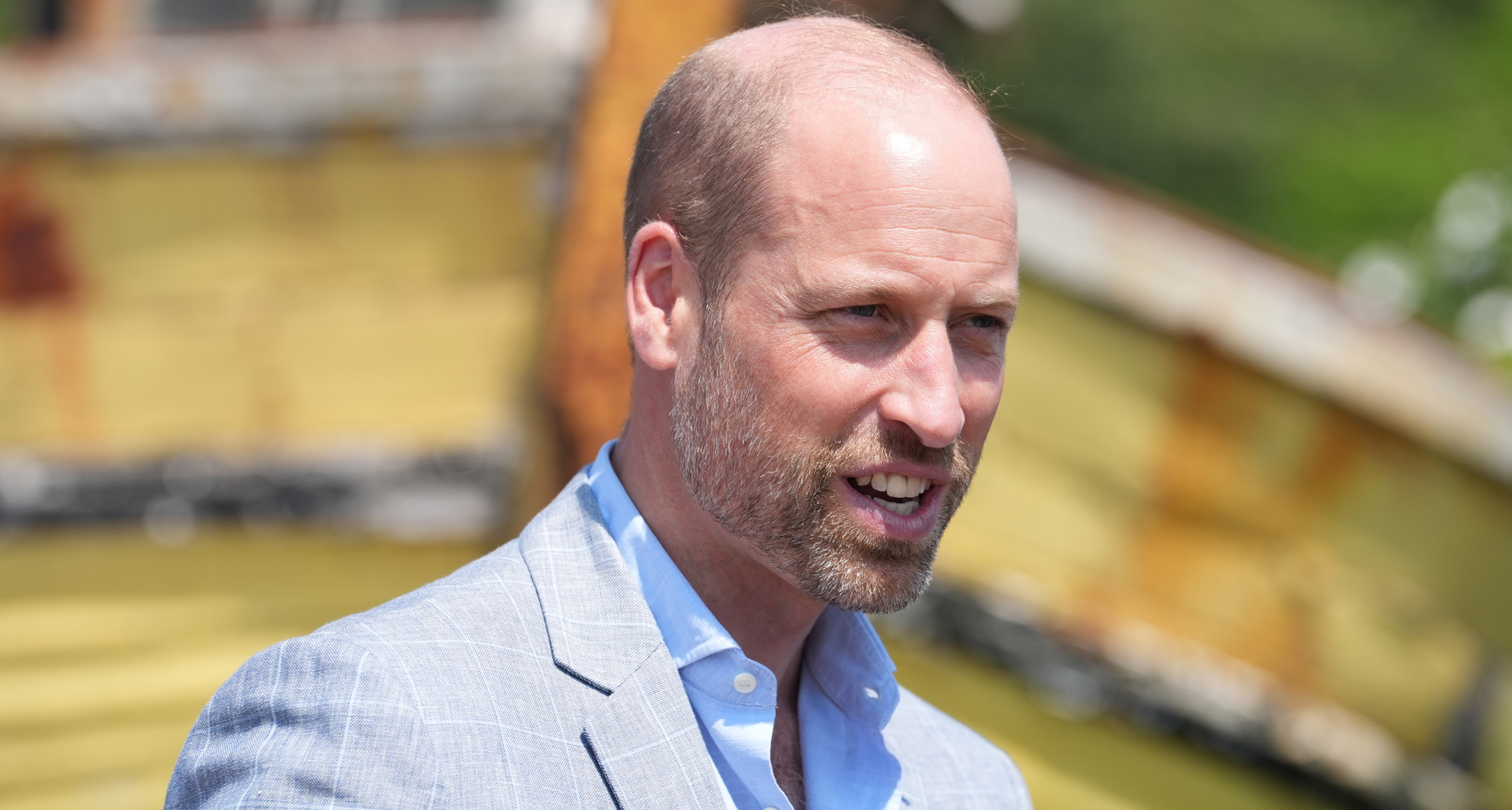 Prince William wearing a light gray suit and blue shirt 