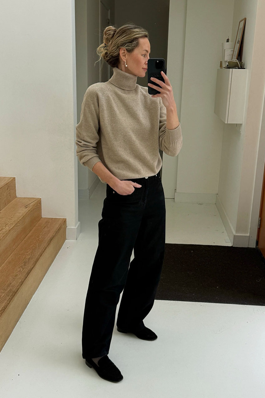 a woman wearing a turtleneck and black pants