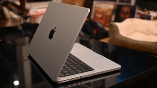 MacBook Pro 14-inch M3 in silver open on a reflective black desk with the lid facing you