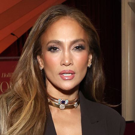 J.lo wears two gold chokers and a brown dress.