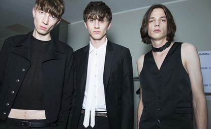 3 male models in monochrome clothing pose for the camera