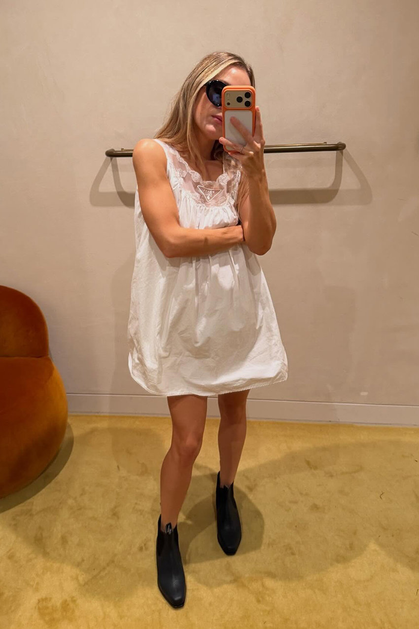 a woman wearing a white babydoll dress and black boots