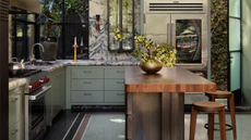 a sage green and stone kitchen with a timber island bench