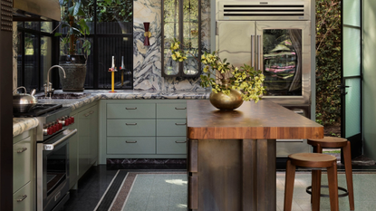 a sage green and stone kitchen with a timber island bench