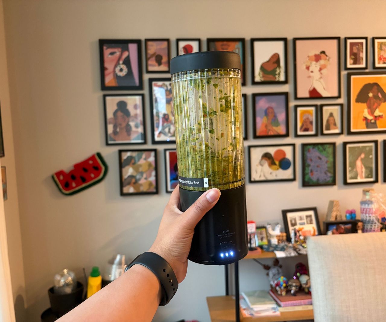 A green smoothie inside a small portable blender with a black base and lid.