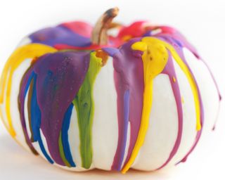 A white pumpkin decorated with colored melted crayon wax