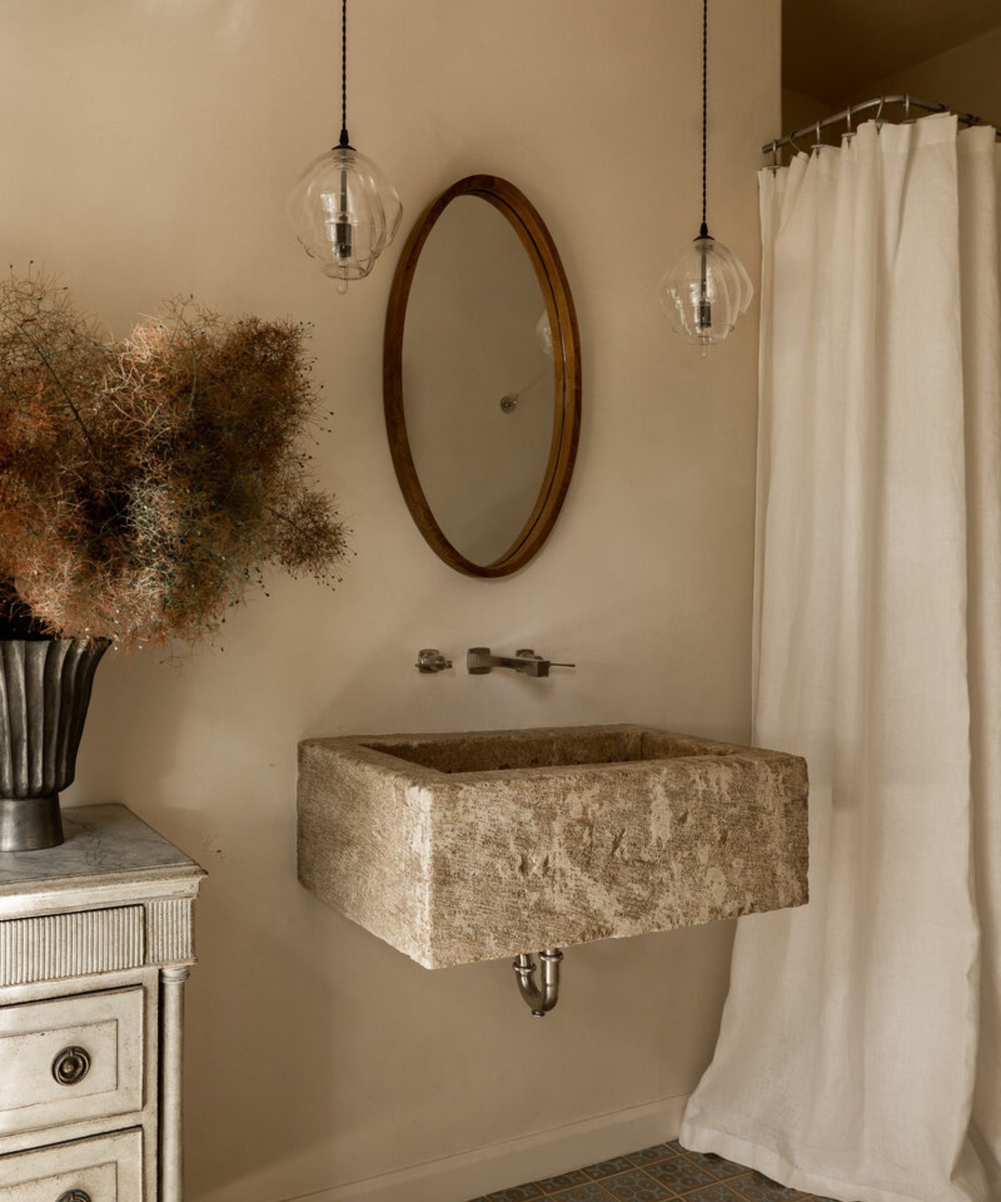 A warm neutral bathroom with a statement sink and pendant lights above the vanity
