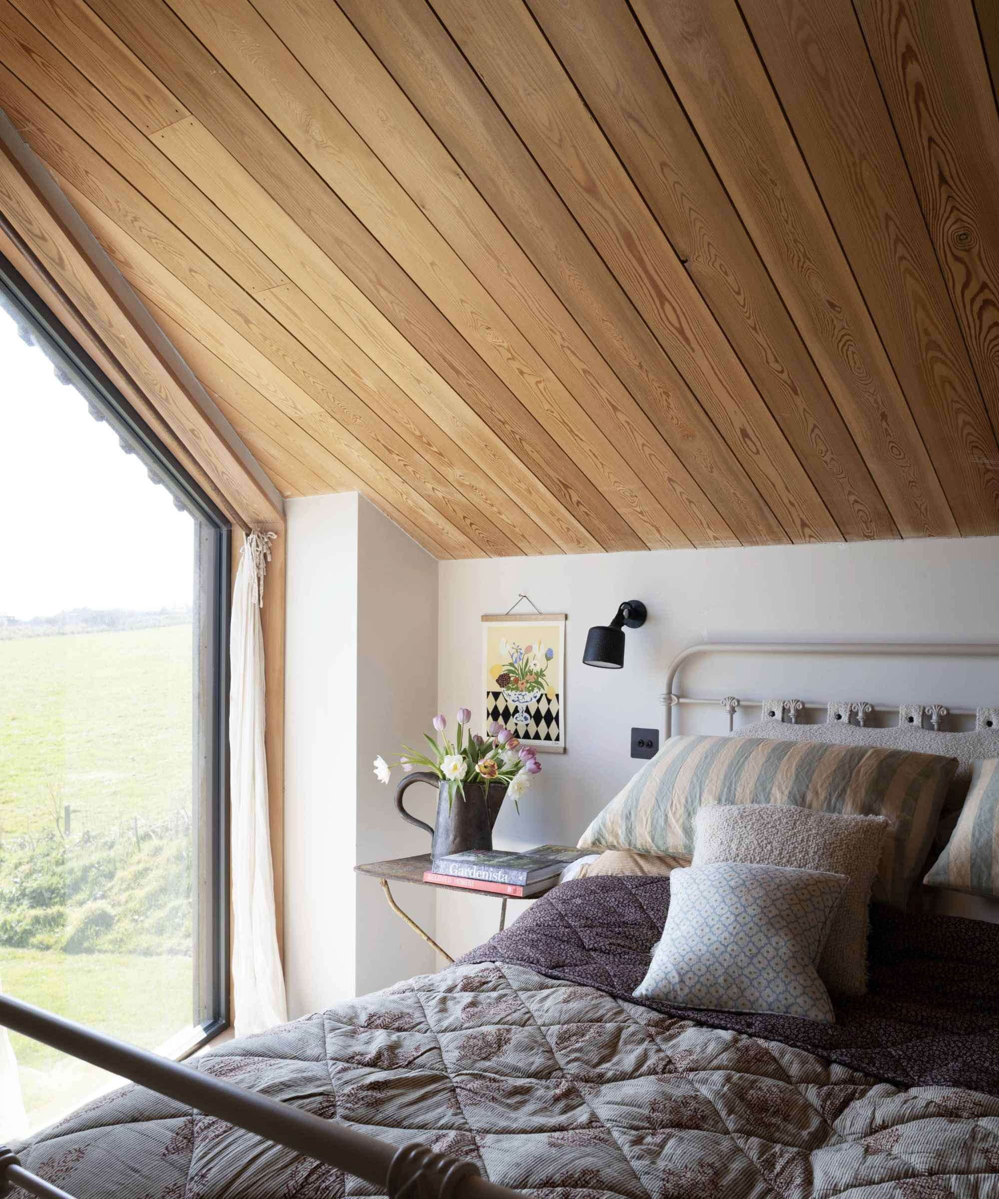bedroom with sloped wooden ceiling and view of field from window
