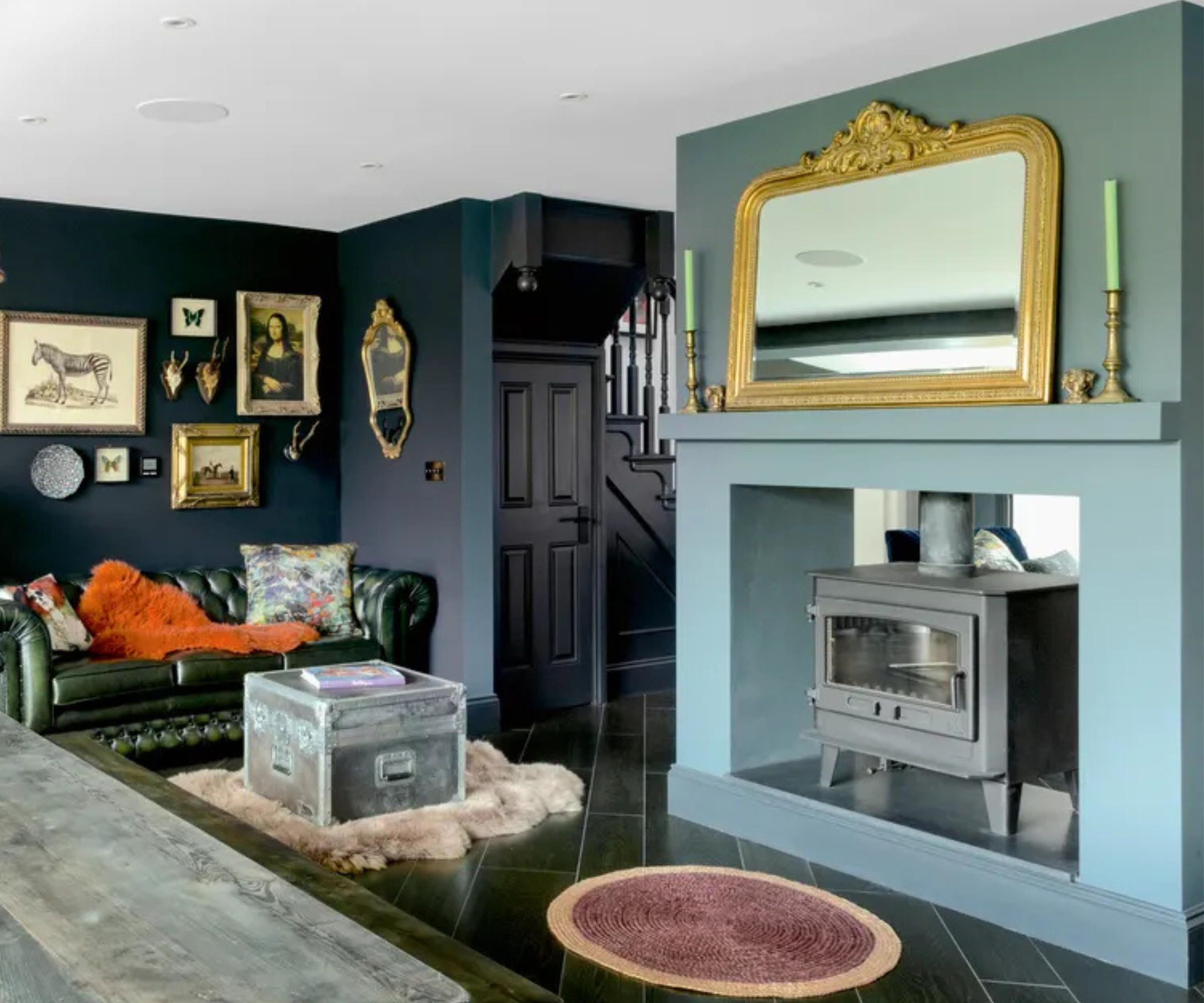 A large log burner with a traditional fireplace surround painted blue