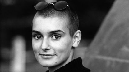 Sinead O'Connor performing on stage with a guitar in 1988