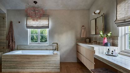 a limewash bathroom with a stone bath and vanity, and a murano glass pink chandelier