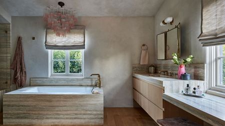 a limewash bathroom with a stone bath and vanity, and a murano glass pink chandelier