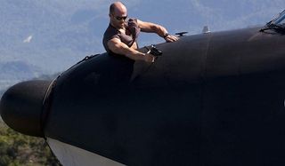 The Expendables Lee aims a gun, while hanging onto the nose of a flying plane