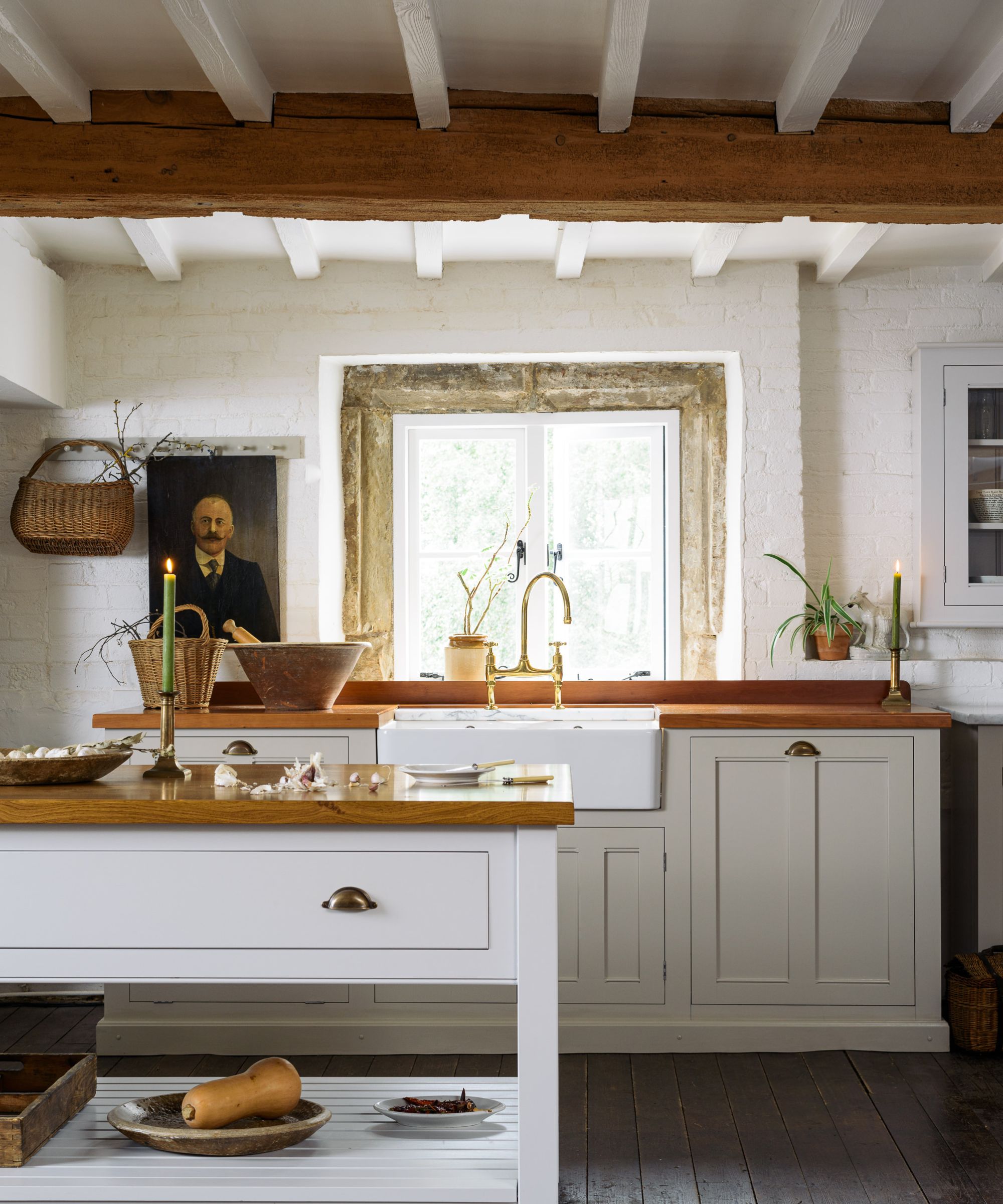 A white country kitchen with wooden countertops and hanging baskets