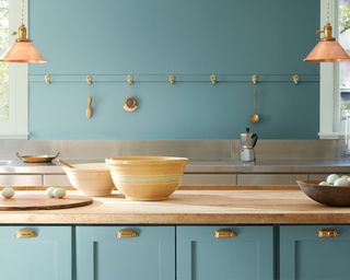 kitchen with teal cabinets, wooden worktops and copper pendant lights