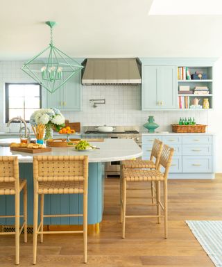 Pale blue kitchen with island and wooden chairs