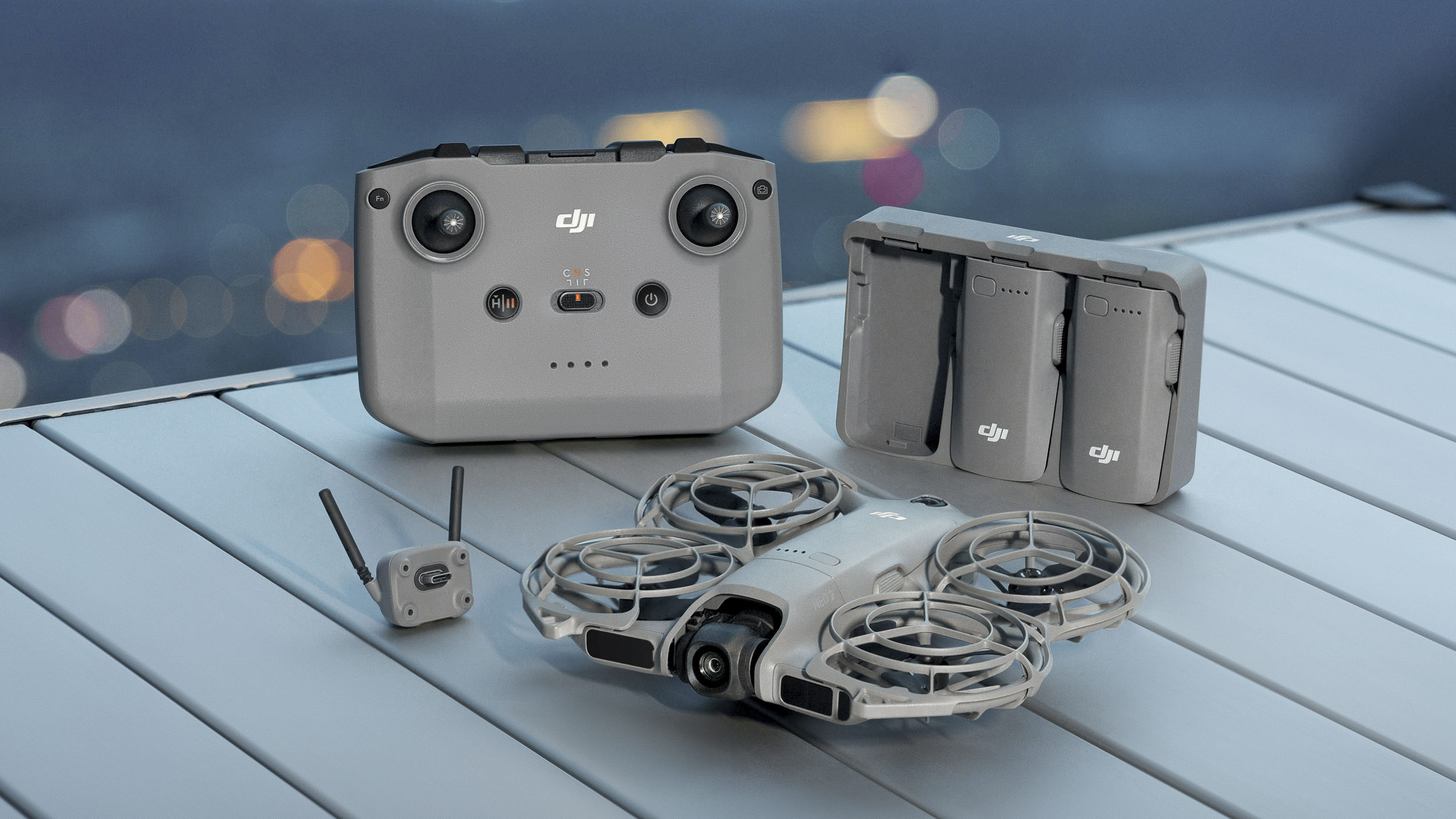 DJI Neo 2 selfie drone on a table alongside controller, battery hub and antenna