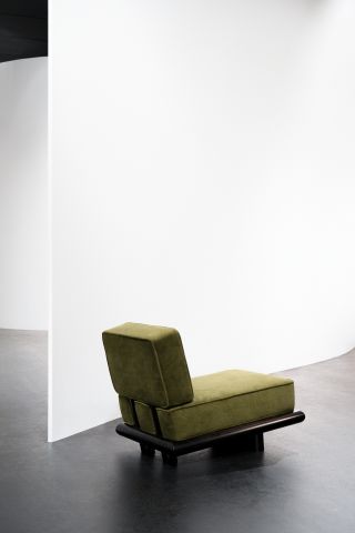 A dark green suede covered chair with a black metal frame.