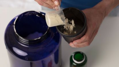 Man dispensing protein powder into a shaker