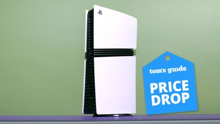 PS5 Pro standing on table with green background with Tom's Guide Price Drop badge