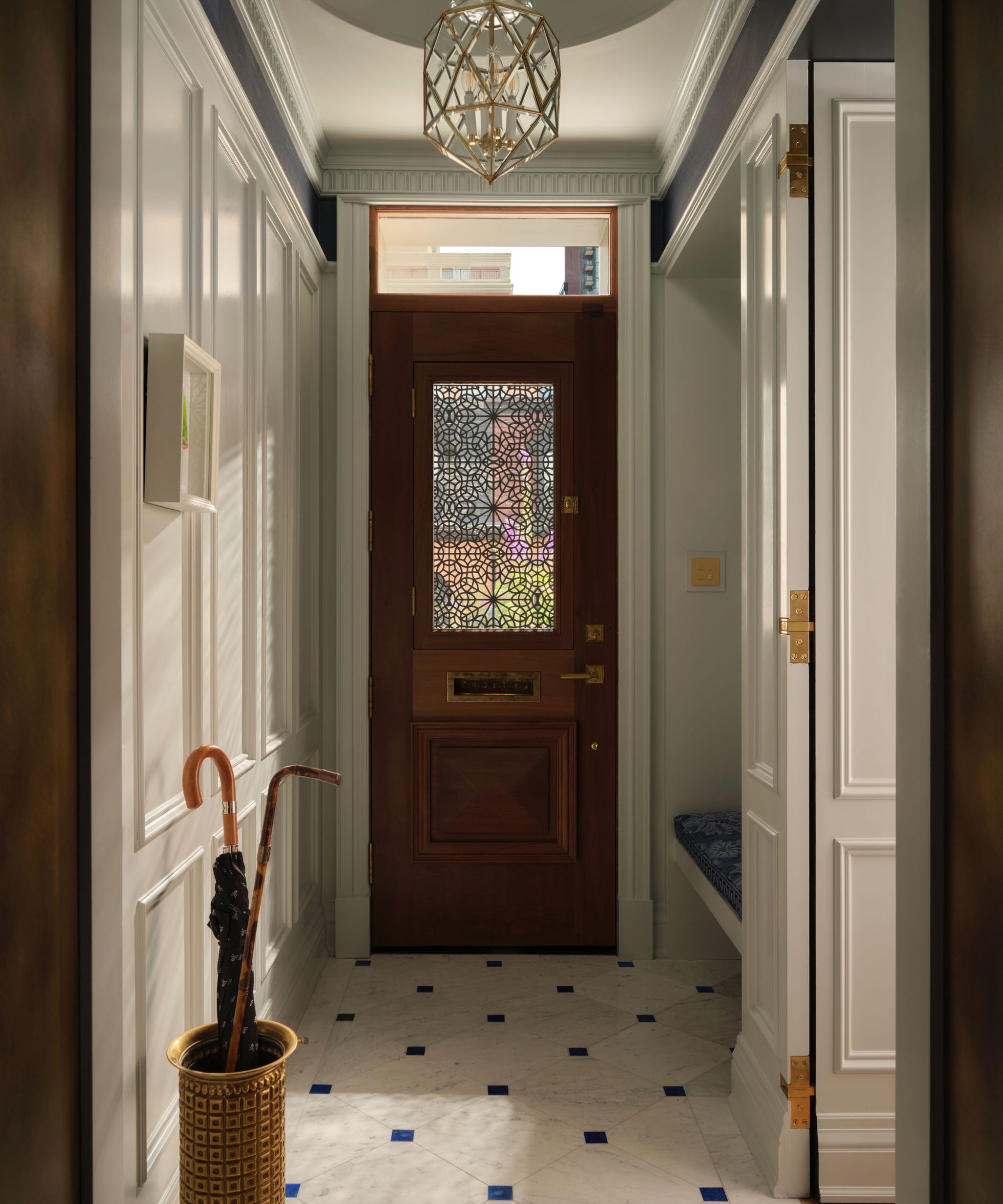 a narrow Victorian foyer in a townhouse with stone floor, a wooden front door and paneled walls
