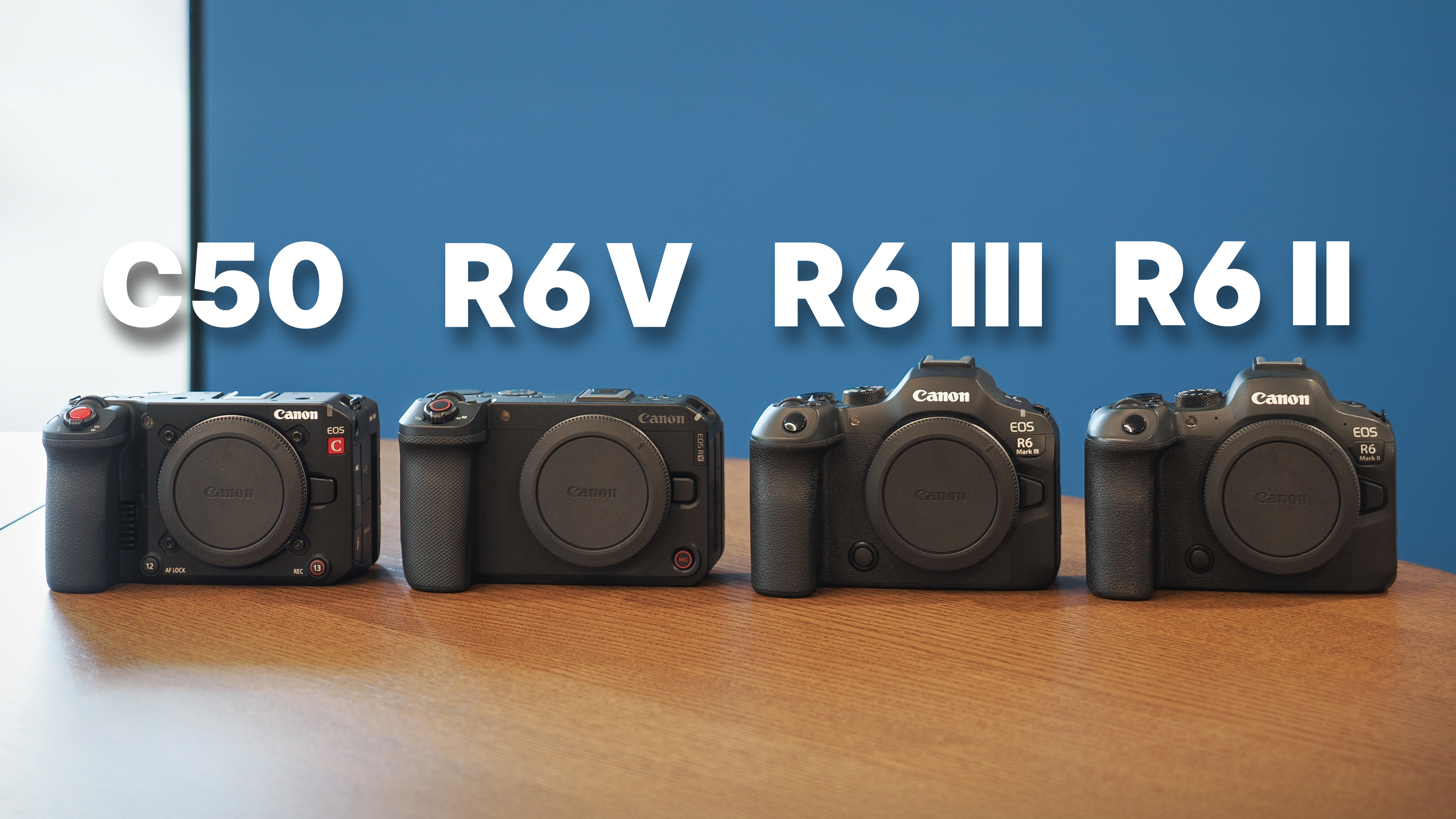The Canon EOS C50 next to the EOS R6 V, R6 Mark III and R6 Mark II, on a wooden surface against a blue background