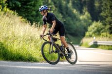 A women rides the Scott Addict 10 out the saddle and up a tight hill