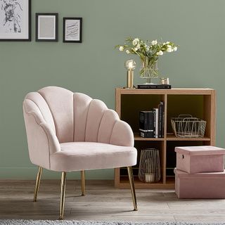 room with frames on green wall and armchair