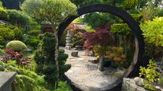 Japanese garden ideas: Japanese style garden with moon gate, rocks, shrubs and trees