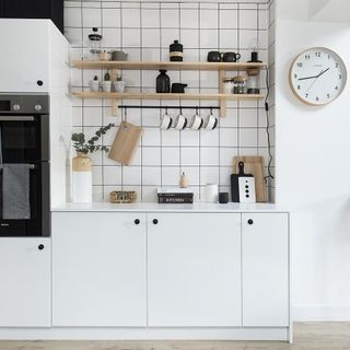 white kitchen with cabinets and wall clock