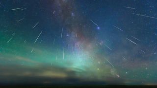 Meteor streaks rain down from the blue-green sky.