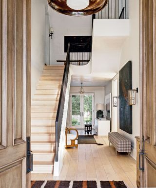 Neutral entrance hall with wooden staircase and wooden floorboards