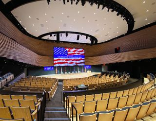 An empty auditorium looking at a stage with a large video wall and other Pro AV solutions from Extron.