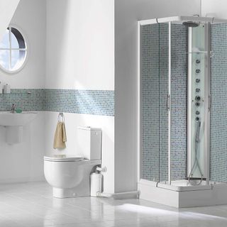 White bathroom with pale blue green mosaic tiles border divider and matching shower tiles, and a porthole window