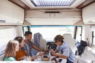 High angle view of family looking at laptop while sitting in camper van.