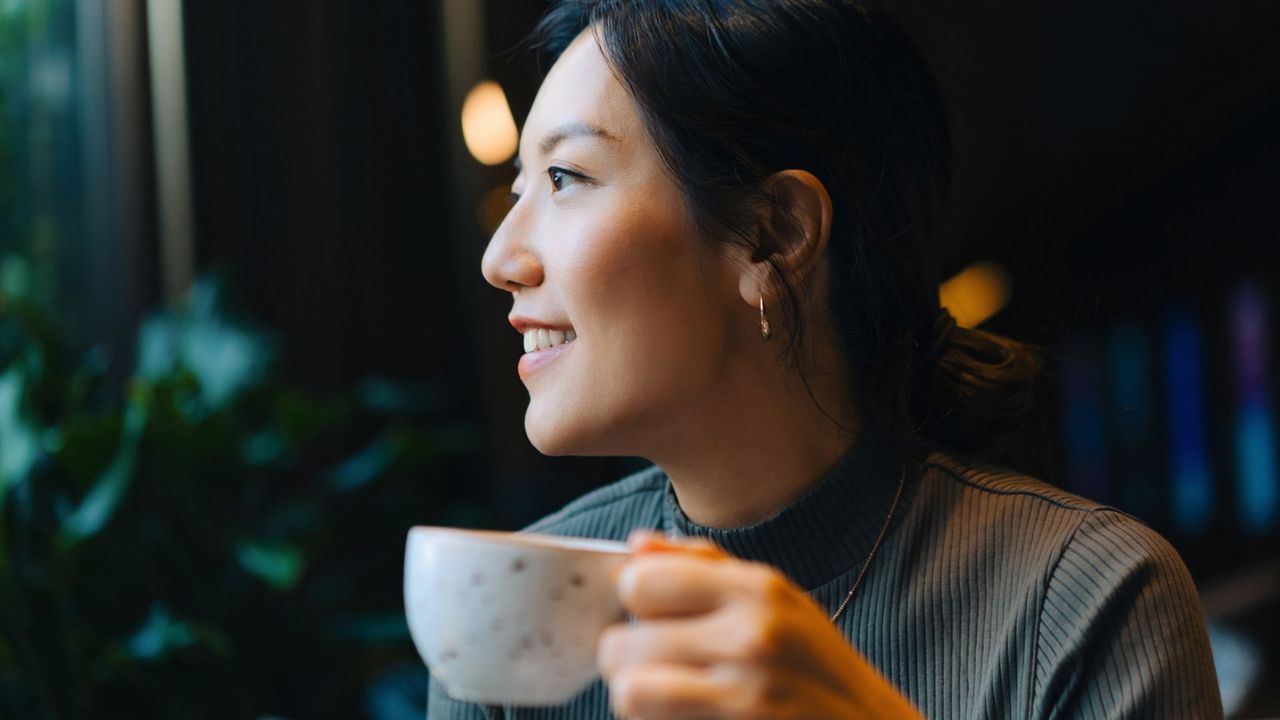 Woman doing Dry January sipping from a cup of hot tea, smiling