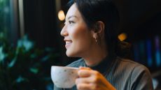 Woman doing Dry January sipping from a cup of hot tea, smiling