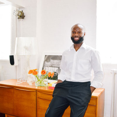 interior designer Augustine Atobatele leaning on a sideboard