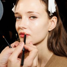 Make-up artist applying lip liner to model's lips