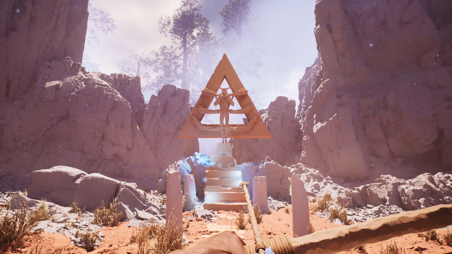 view of a striking, triangular sculpture of man being held down by reptilian claws at the top of a stairway to nowhere, all in the center of this red clay canyon
