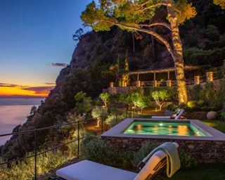 pool area and terraces lit at night on a hillside mediterranean sea facing garden