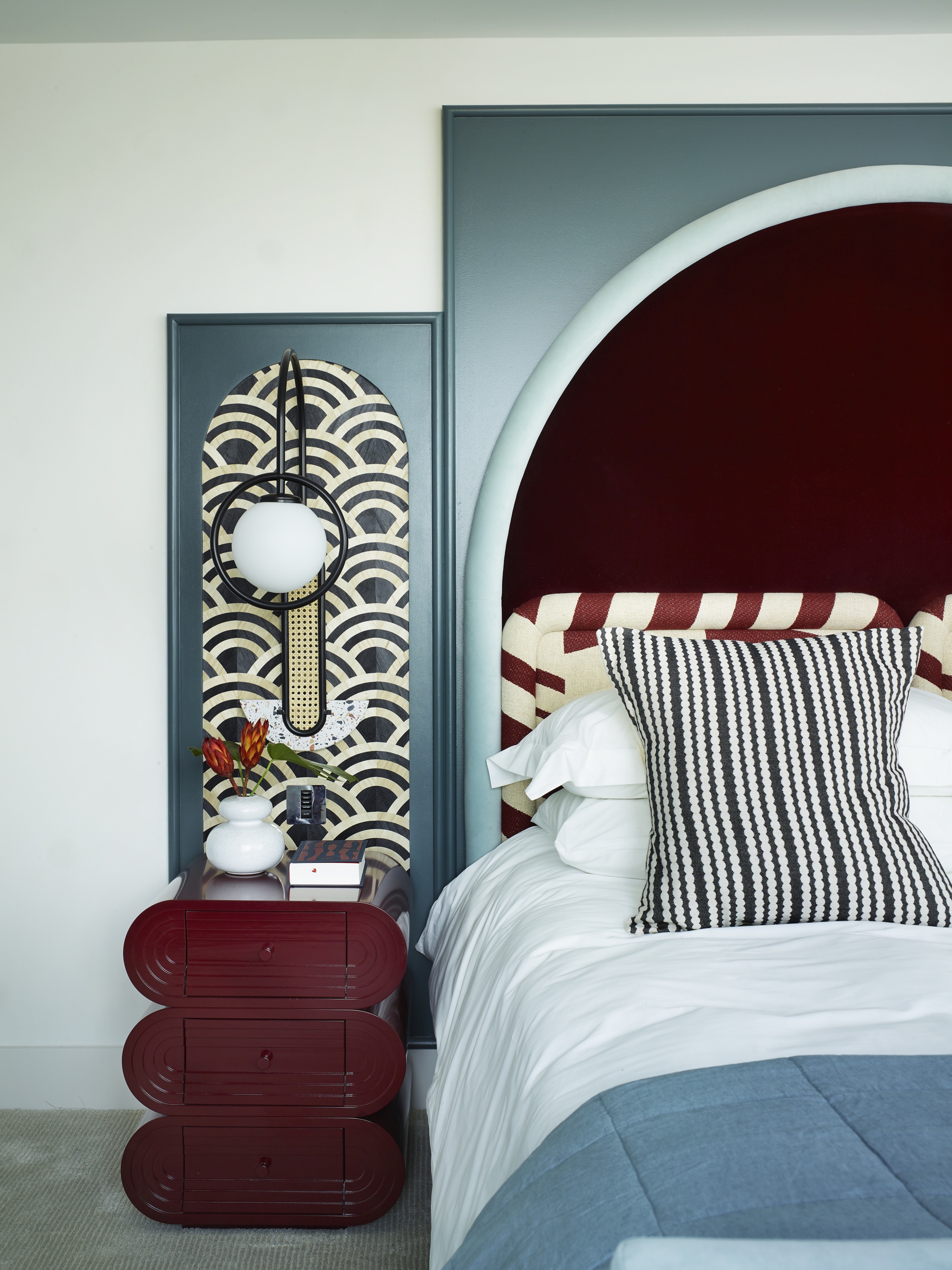 Light blue bedroom with burgundy headboard and burgundy bedside table