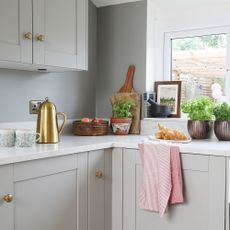 Grey shaker kitchen with brass handles and white worktop