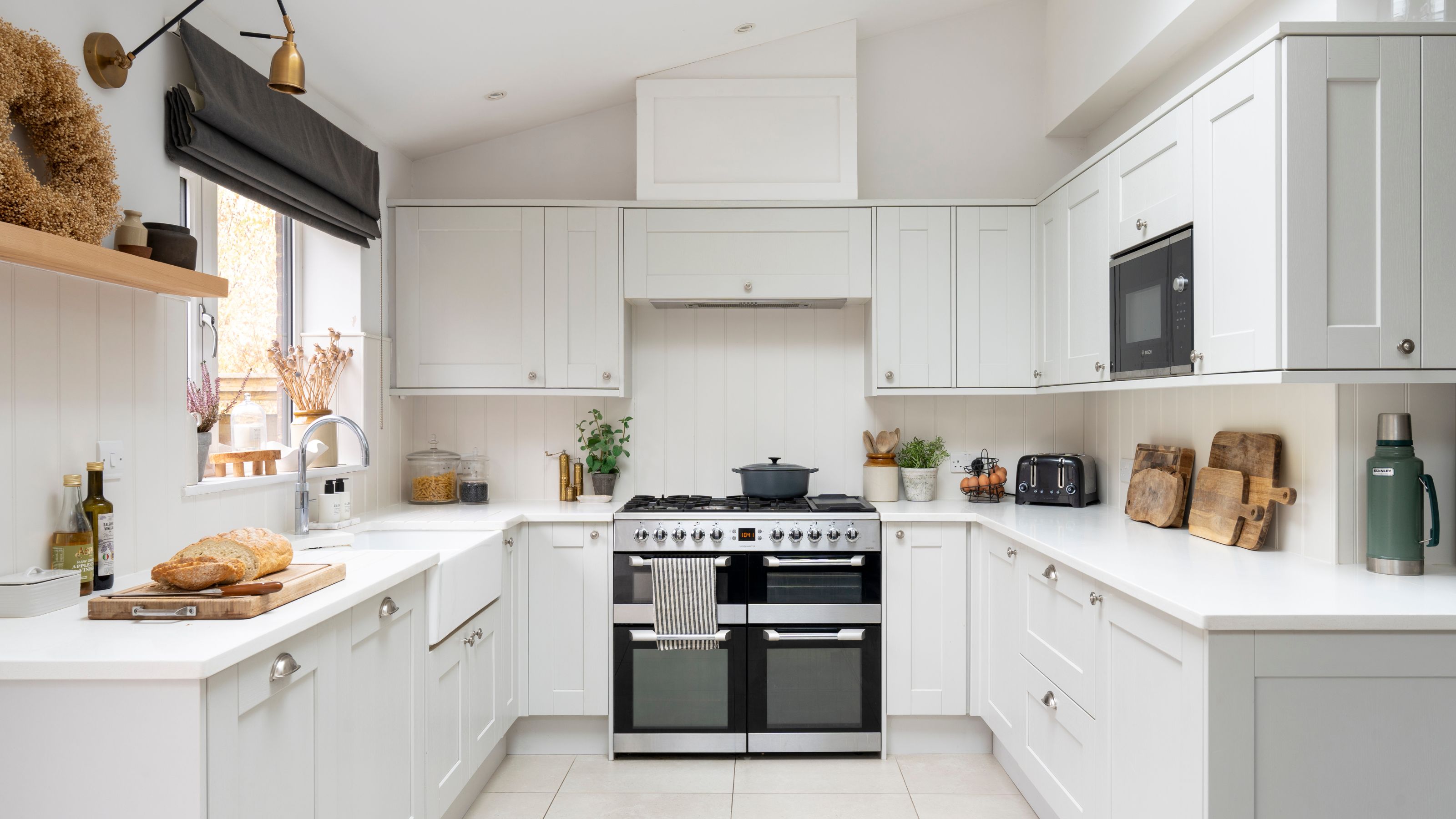 White painted kitchen with U-shaped white cabinets and a white countertop, with a double range oven in the middle