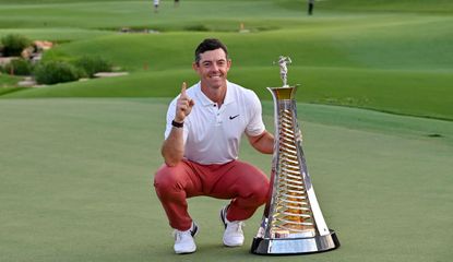 Rory McIlroy poses by the Race to Dubai trophy