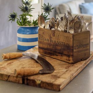 An antique wooden chopping board with a knife and a vase of thistle