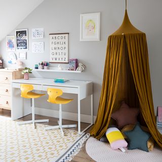 Kids room with bronze canopy over cushions and double white desk